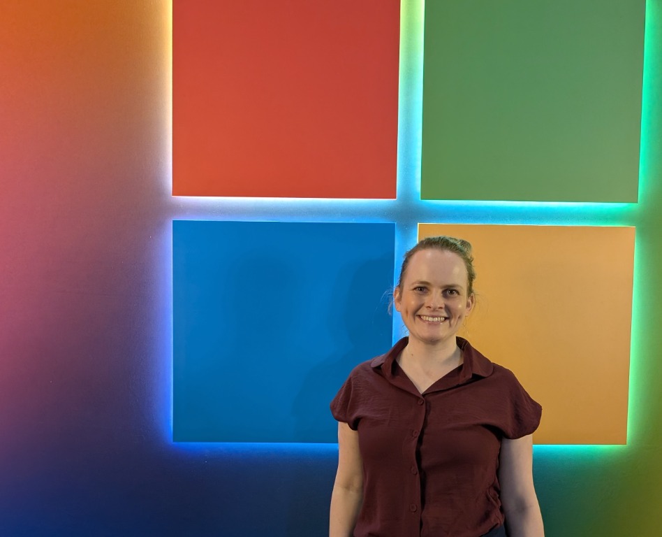 Renee Noble standing in front of an illuminated Microsoft logo